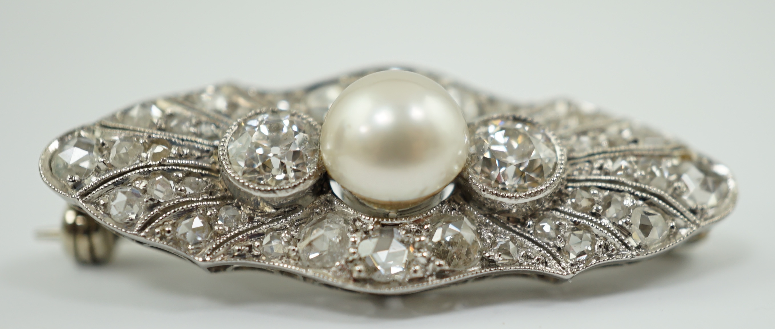 A Belle Epoque white gold, single stone split pearl and millegrain set diamond cluster lozenge shaped brooch